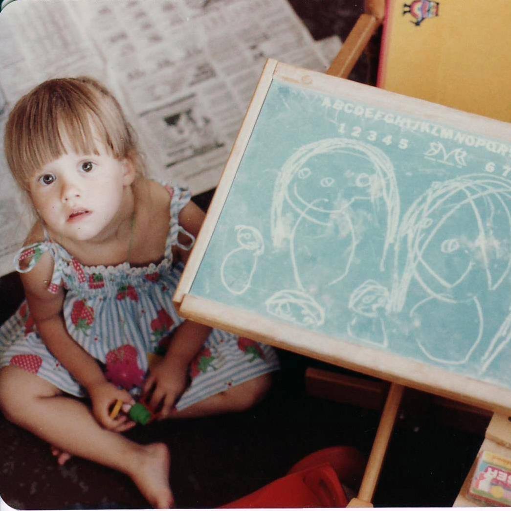 Stephanie Watson at age three, beside her chalkboard drawing